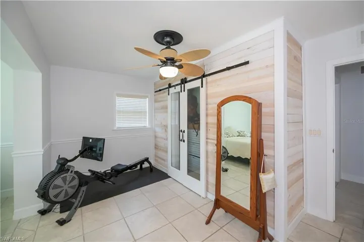 Workout area featuring light tile patterned floors, a ceiling fan, and a barn door
