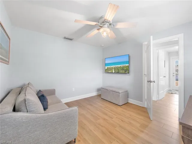 Sitting room with light wood finished floors and a ceiling fan