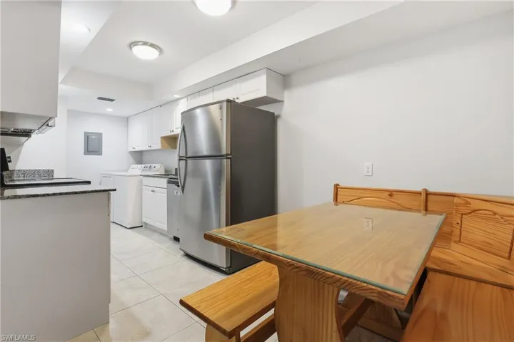Kitchen with white cabinets, appliances with stainless steel finishes, washer / dryer, light tile patterned flooring, and a tray ceiling