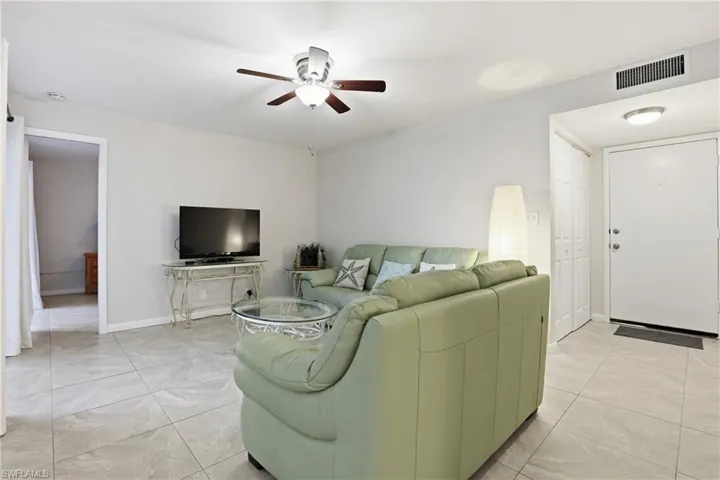 Living area featuring a ceiling fan and light tile patterned flooring