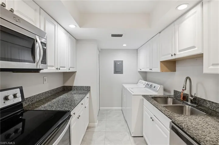 Laundry room featuring recessed lighting, washing machine and clothes dryer, light tile patterned floors, and electric panel