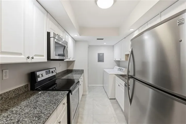 Kitchen featuring stainless steel appliances, white cabinetry, recessed lighting, light tile patterned flooring, and independent washer and dryer