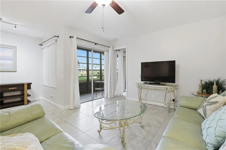 Tiled living room with a ceiling fan and baseboards