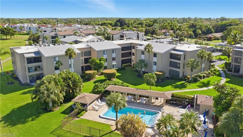 Drone / aerial view of a pool area and apartment complex / building