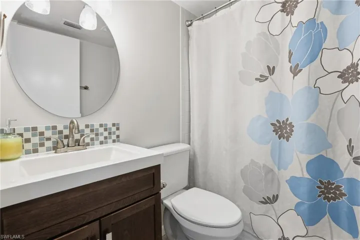 Bathroom with vanity, a shower with shower curtain, and decorative backsplash