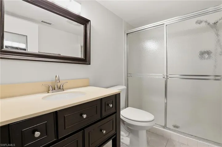 Full bathroom with light tile patterned floors, vanity, and a shower stall