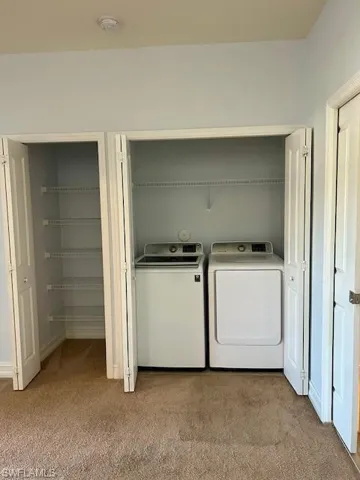 Laundry closet featuring a washer and dryer, accompanied by a separate storage closet with wire shelving, all set on a neutral carpeted floor