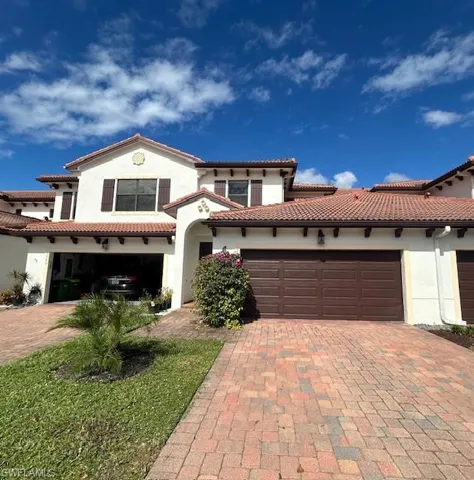 Stucco exterior residence featuring a tile roof, decorative shutters, and an arched entry