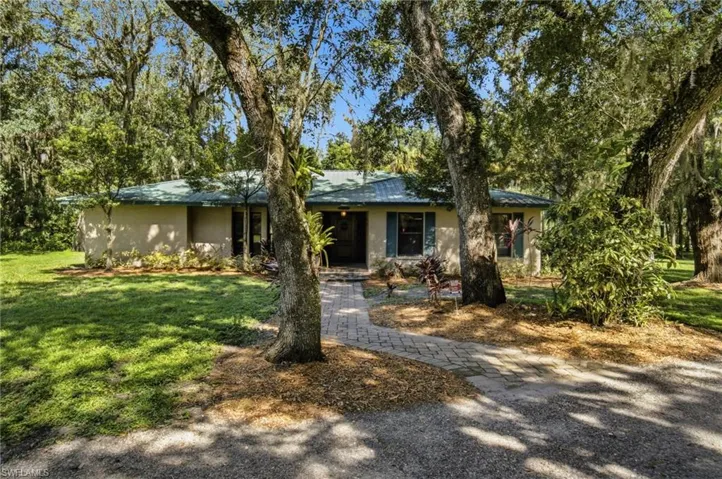 Daytime exterior view showing the residence beneath mature shade trees