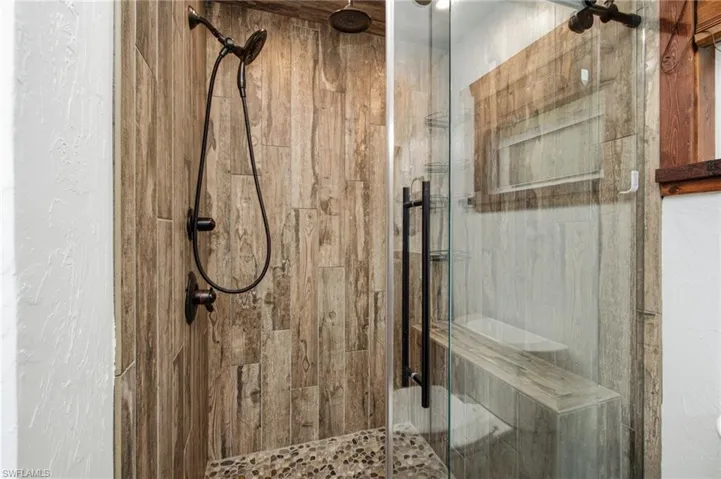 Glass enclosed shower with wood look wall tile and contrasting fixtures