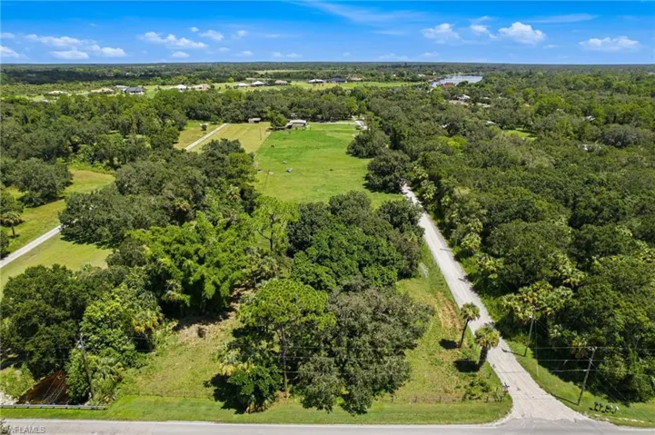 Wide aerial perspective of the property and surrounding wooded landscape