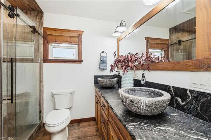 Primary bathroom with wood vanity, vessel sink and glass enclosed shower