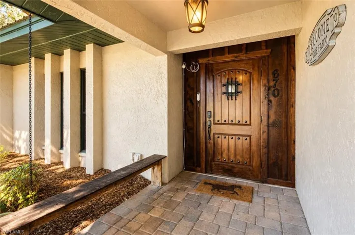 Closer view of the covered entry and carved wood front door