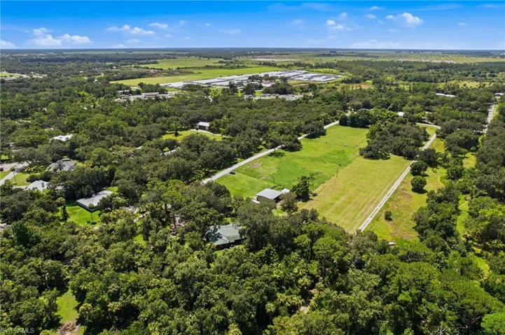 Wide aerial perspective of the property and surrounding wooded landscape