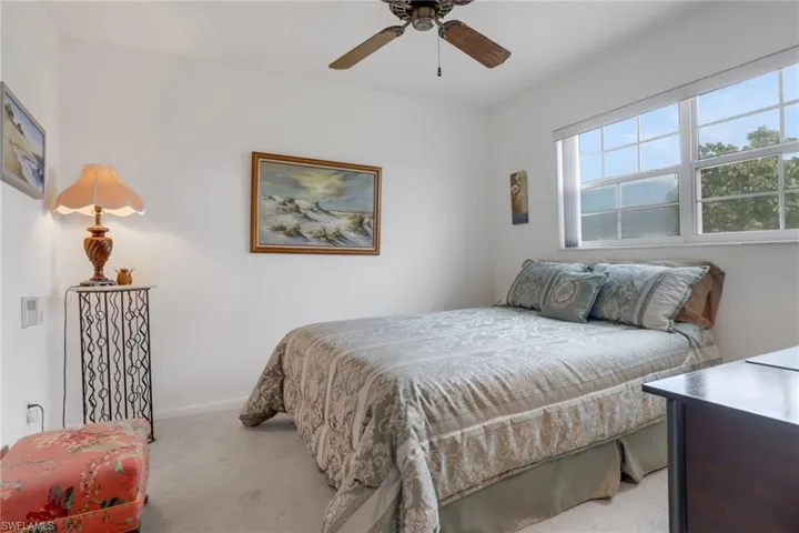 Guest bedroom with large window and light colored carpet