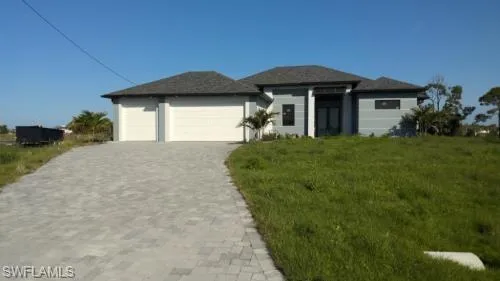 View of front of home with a garage and a front lawn