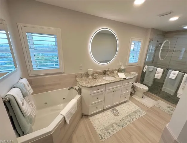 Bathroom with vanity, a shower stall, light wood finished floors, and a jetted tub