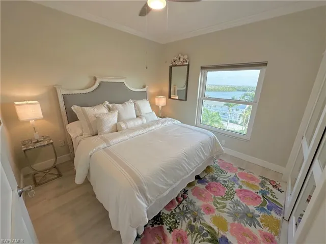 Bedroom with light wood-type flooring, ornamental molding, and a ceiling fan