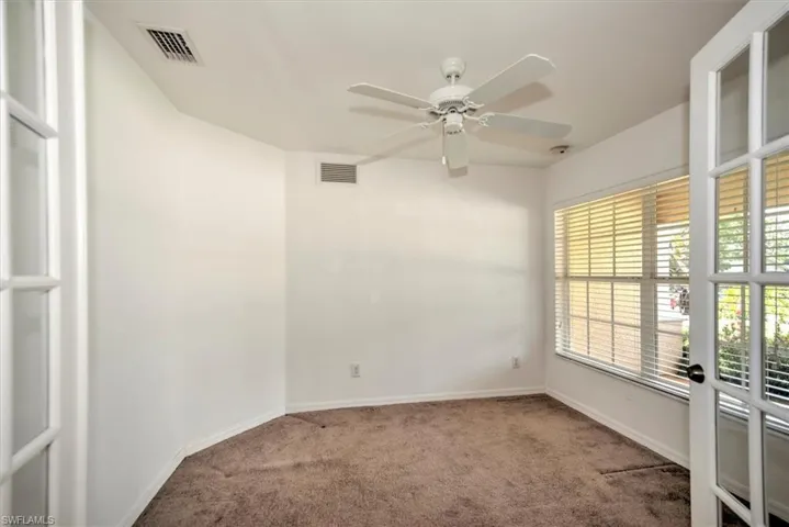 Den with ceiling fan and french double doors