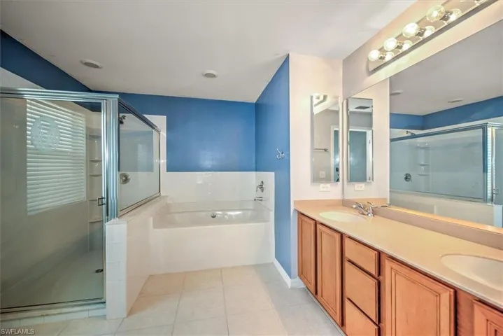 Bathroom featuring dual vanity, shower with separate bathtub, and tile floors