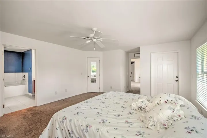 Bedroom with multiple windows, ceiling fan, and ensuite bath