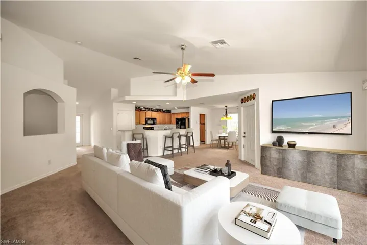 Great Room Staged featuring high vaulted ceiling, light carpet, ceiling fan, and a healthy amount of sunlight