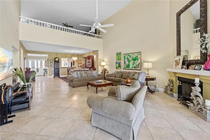 Tiled living room with ceiling fan with notable chandelier and a towering ceiling