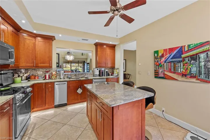 Kitchen with light stone counters, stainless steel appliances, decorative backsplash, and a center island