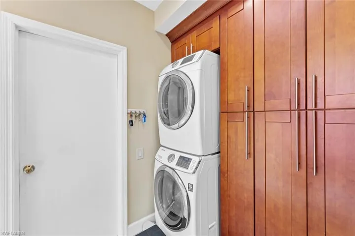 Washroom featuring stacked washer / drying machine and cabinets
