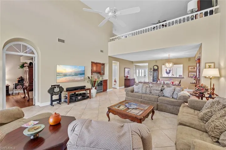Tiled living room with a high ceiling and ceiling fan with notable chandelier