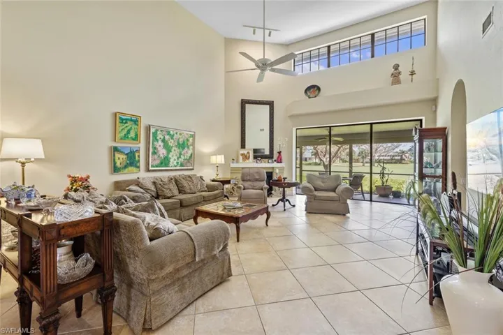 Living room featuring ceiling fan, a towering ceiling, and light tile patterned floors