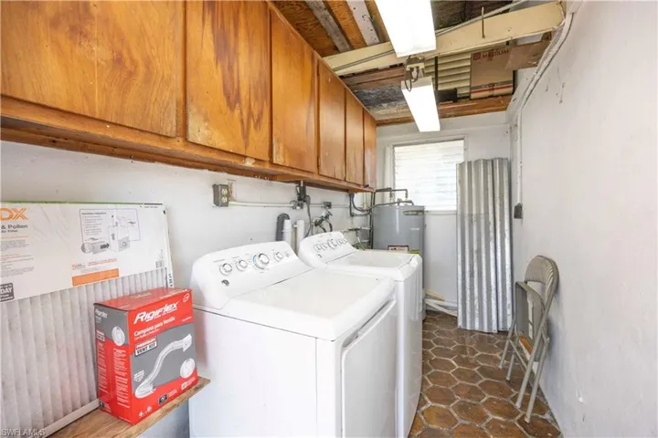 Washroom featuring washer and clothes dryer, cabinet space, and electric water heater