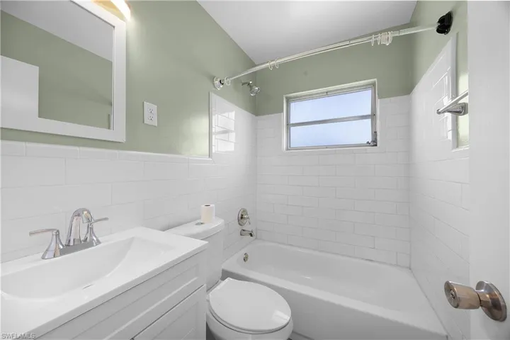 Full bathroom with shower / tub combination, vanity, and tile walls