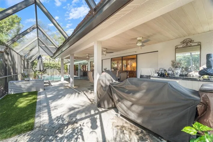 View of patio featuring glass enclosure, a ceiling fan, an outdoor pool, and a grill