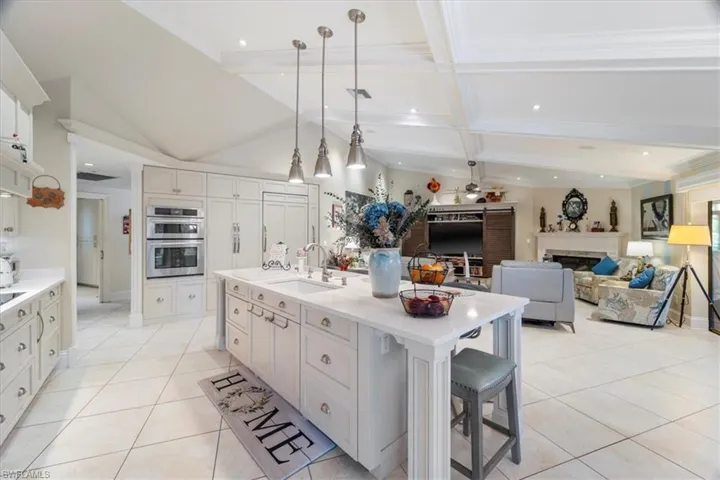 Kitchen featuring light countertops, light tile patterned floors, a fireplace, stainless steel double oven, and a sink