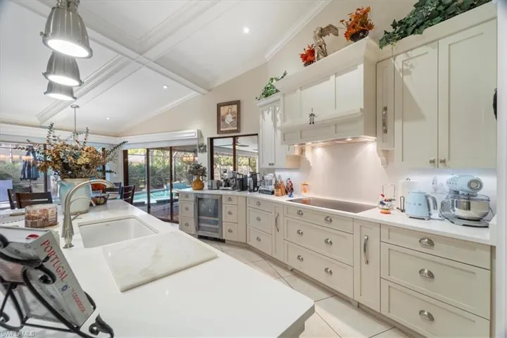 Kitchen featuring black electric stovetop, light tile patterned floors, beverage cooler, and ornamental molding