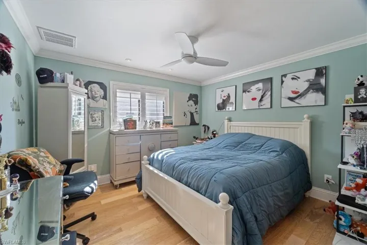 Bedroom featuring light wood finished floors, visible vents, crown molding, and baseboards