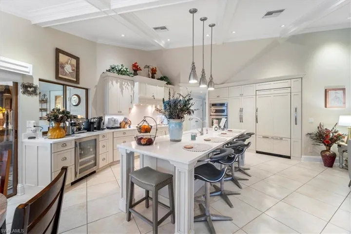 Kitchen featuring visible vents, beverage cooler, a towering ceiling, and light countertops