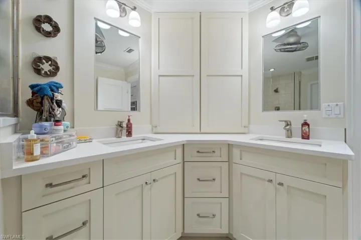 Bathroom featuring double vanity, visible vents, ornamental molding, and a sink
