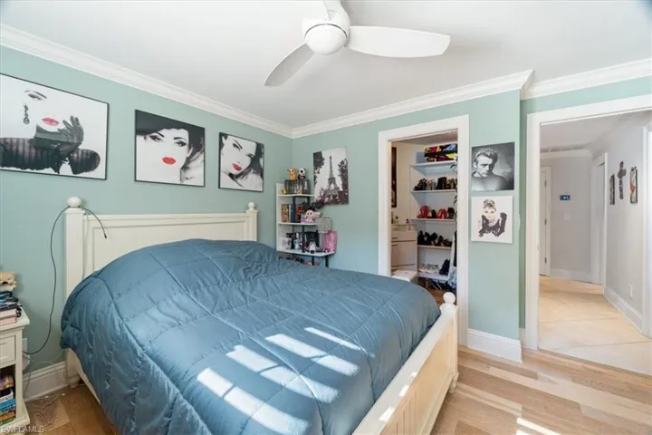 Bedroom featuring baseboards, a ceiling fan, light wood-style floors, and ornamental molding