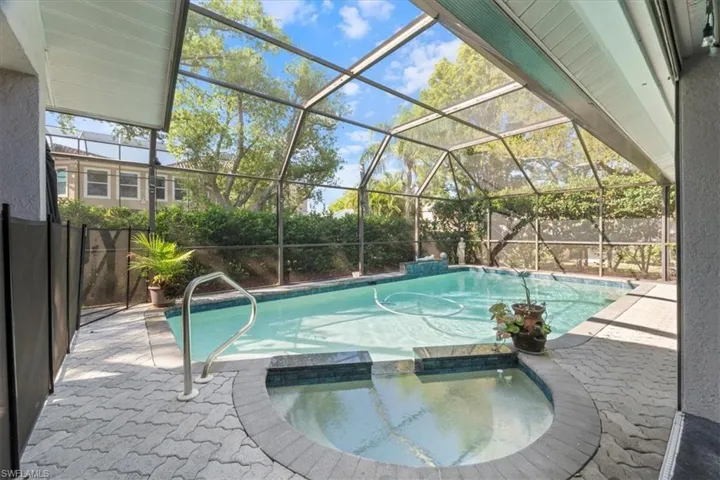 View of pool featuring a patio, fence, a lanai, and a pool with connected hot tub