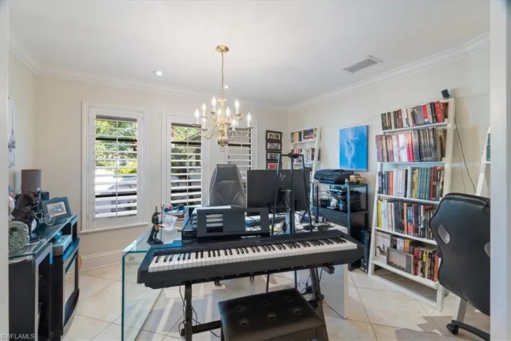 Home office with visible vents, crown molding, baseboards, light tile patterned flooring, and a notable chandelier