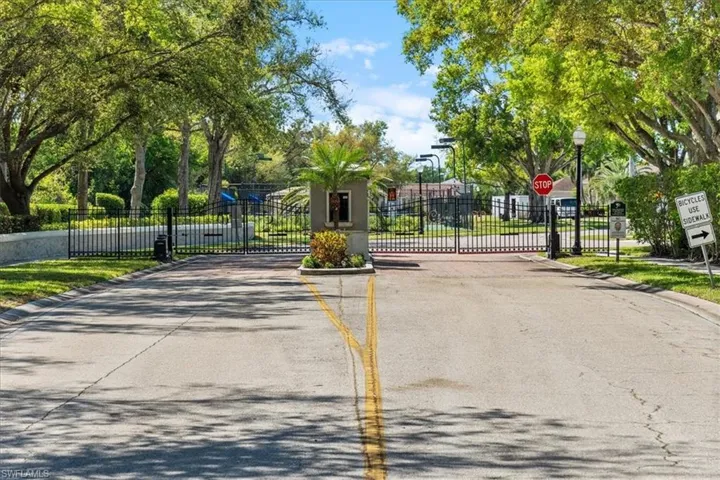 View of road with traffic signs, curbs, a gate, a gated entry, and street lighting