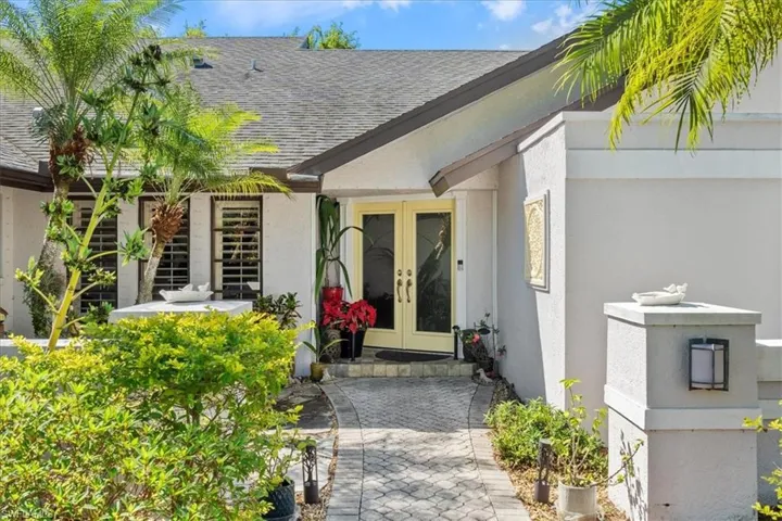 Property entrance with stucco siding, french doors, and a shingled roof