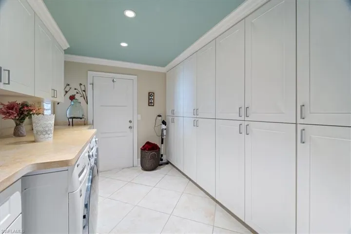 Kitchen featuring light tile patterned floors, recessed lighting, light countertops, white cabinets, and crown molding