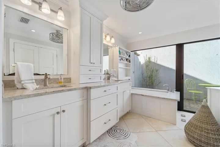 Full bath with tile patterned floors, visible vents, a tub to relax in, ornamental molding, and vanity