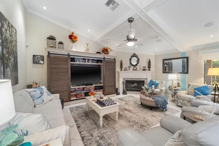 Living area featuring visible vents, ornamental molding, a fireplace, light tile patterned floors, and ceiling fan