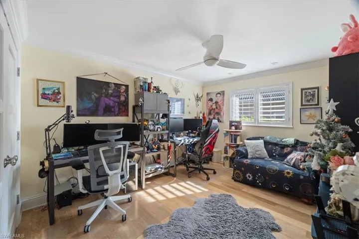 Office space featuring a ceiling fan, wood finished floors, and ornamental molding