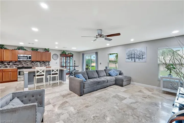 Living room with recessed lighting, a ceiling fan, and light stone finish floors