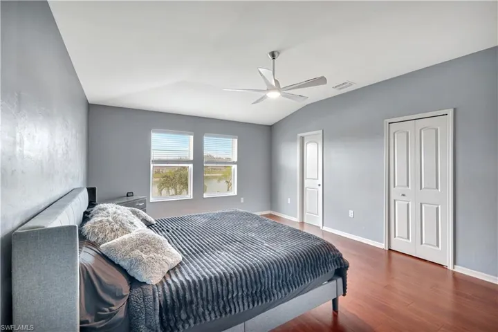 Bedroom with dark wood-style flooring, vaulted ceiling, and a ceiling fan